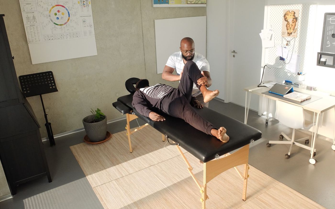 A clinician guiding a patient through a leg and hip assessment in a treatment room