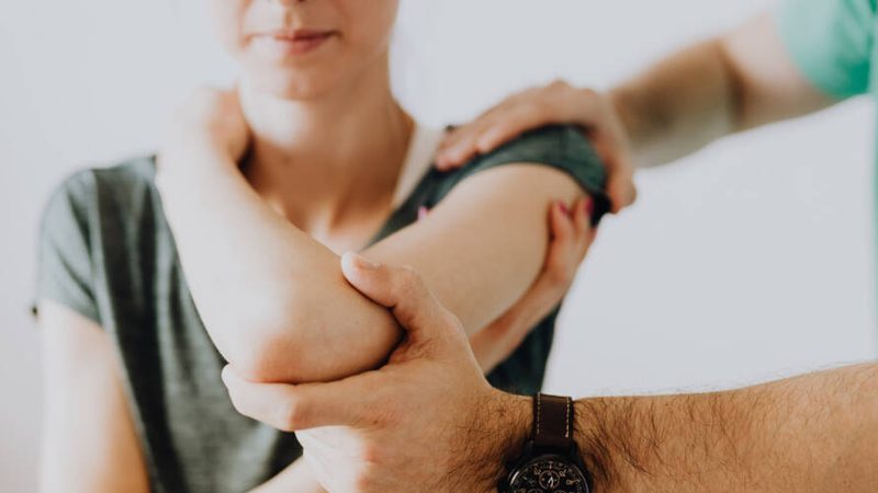 A clinician working on a patient's shoulder and arm
