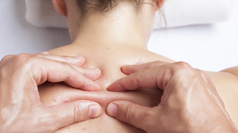 Close-up of hands performing soft tissue therapy on a patient's neck
